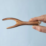 An adult's hand holding up a Bumbu Toys Black Poplar Branch.