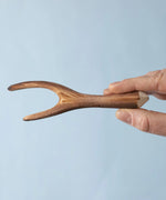An adult's hand holding up a Bumbu Toys Black Poplar Branch.