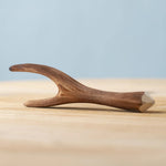 Bumbu Toys Black Poplar Branch placed on a wooden surface in front of a blue wall.
