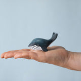 A Bumbu Toys Baby Blue Whale placed on the palm of an adult's hand to show scale. 