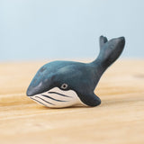 A Bumbu Toys Baby Blue Whale placed on a wooden surface. We have a wide range of Bumbu handmade wooden figures here at Babipur.
