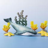 A Bumbu Toys Blue Whale handmade wooden toy figure placed at the centre of a underwater themed small world play scene. 
