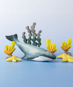 A Bumbu Toys Blue Whale handmade wooden toy figure placed at the centre of a underwater themed small world play scene. 