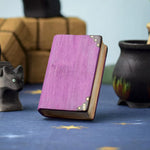 A Bumbu Toys Large purple Book shown at the centre of a Halloween themed play scene. Other Halloween themed wooden toys can be seen in the background. 