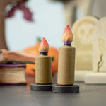 Bumbu Toys wooden Candle figures Set. The candles have a beige colour, on a black coloured base with a flame on the top. One candle is taller than the other. The candles are placed at the front and centre of a Halloween themed small world play set up. 