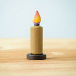A single candle from the Bumbu Toys wooden Candle figures Set. The candle has been placed on a wooden surface. 
