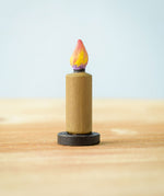 A single candle from the Bumbu Toys wooden Candle figures Set. The candle has been placed on a wooden surface. 