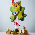 Bumbu Toys wooden Butterflies, placed on a Bumbu Birch Tree surrounded by Bumbu Rabbits, flowers and grass.