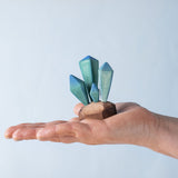 A Bumbu wooden crystal figure placed in an adult's palm to show scale. 