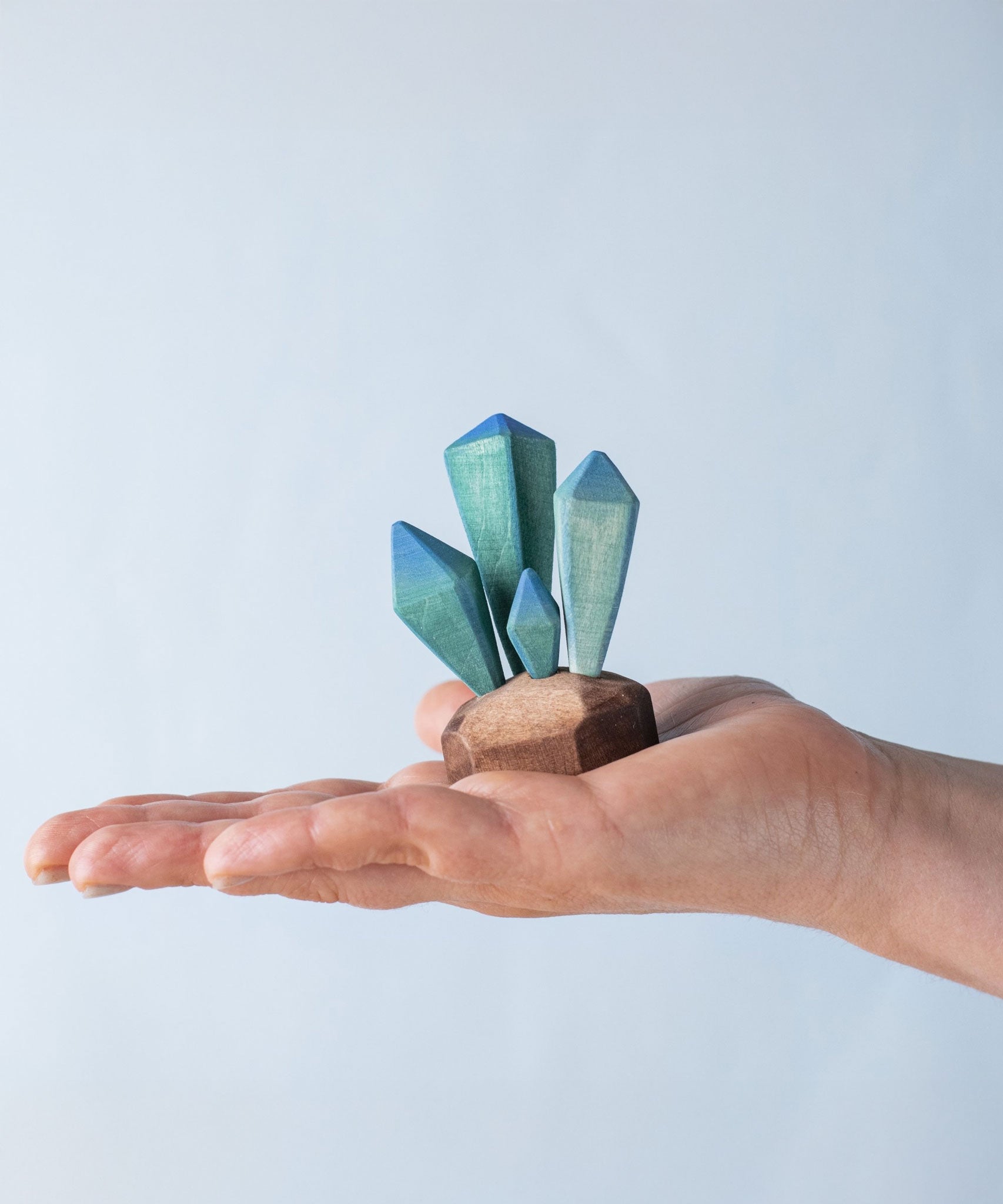 A Bumbu wooden crystal figure placed in an adult's palm to show scale. 