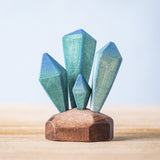 A Bumbu Toys Crystals wooden figure placed on a wooden surface. These handmade wooden crystals are perfect for use in setting scenes and small world play or just for decoration and display. Check out our full range of wooden toy scenery at Babipur. 