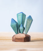 A Bumbu Toys Crystals wooden figure placed on a wooden surface. These handmade wooden crystals are perfect for use in setting scenes and small world play or just for decoration and display. Check out our full range of wooden toy scenery at Babipur. 