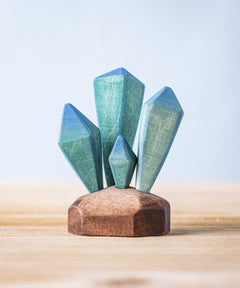 A Bumbu Toys Crystals wooden figure placed on a wooden surface. These handmade wooden crystals are perfect for use in setting scenes and small world play or just for decoration and display. Check out our full range of wooden toy scenery at Babipur. 