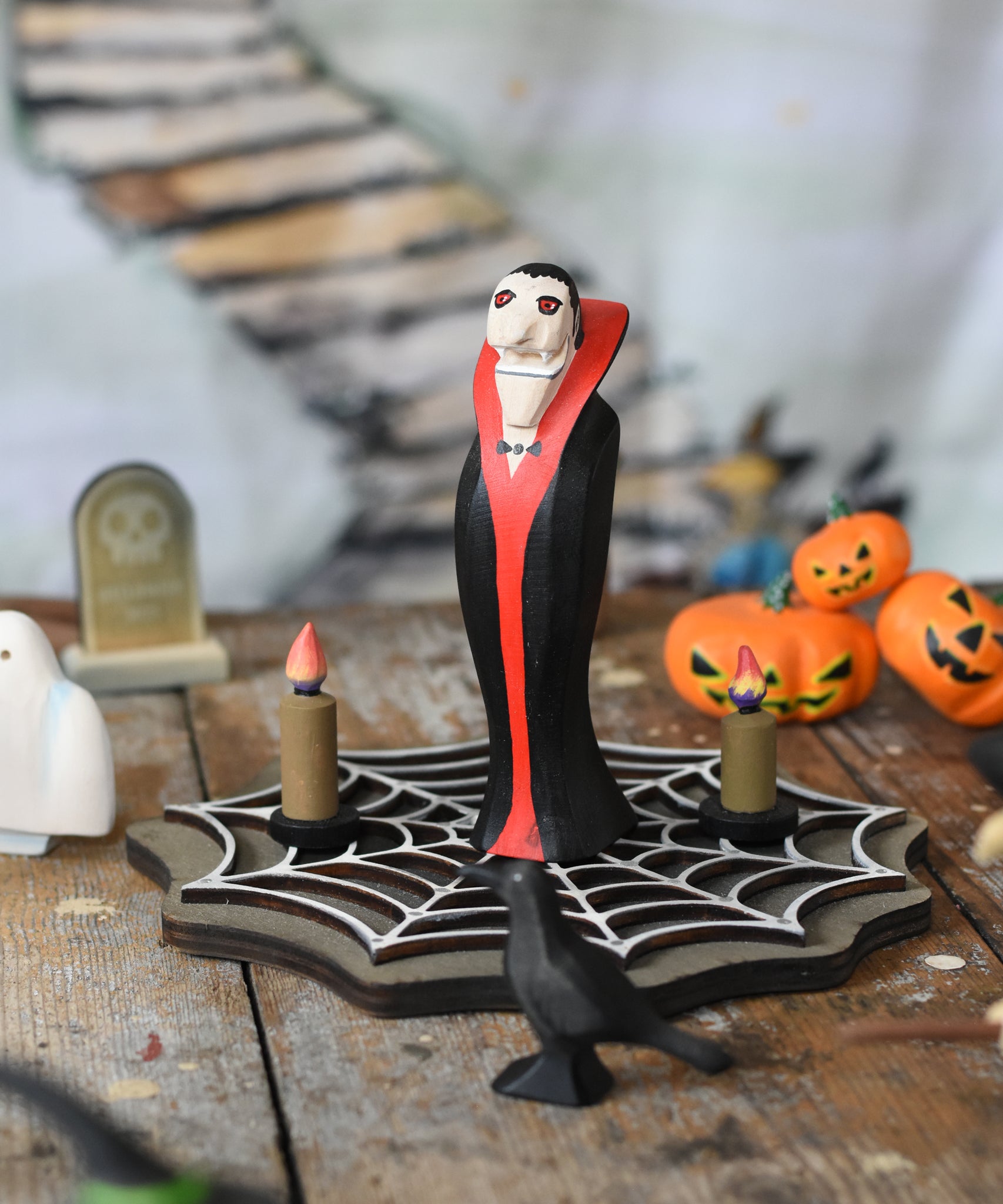 Bumbu Toys Dracula The Vampire Wooden Halloween Figure placed on a wooden cobweb in the middle of a small world play scene with Bumbu Halloween and Autumn themed toys.
These expertly hand crafted items are part of a large range of wooden toys available here at Babipur.  