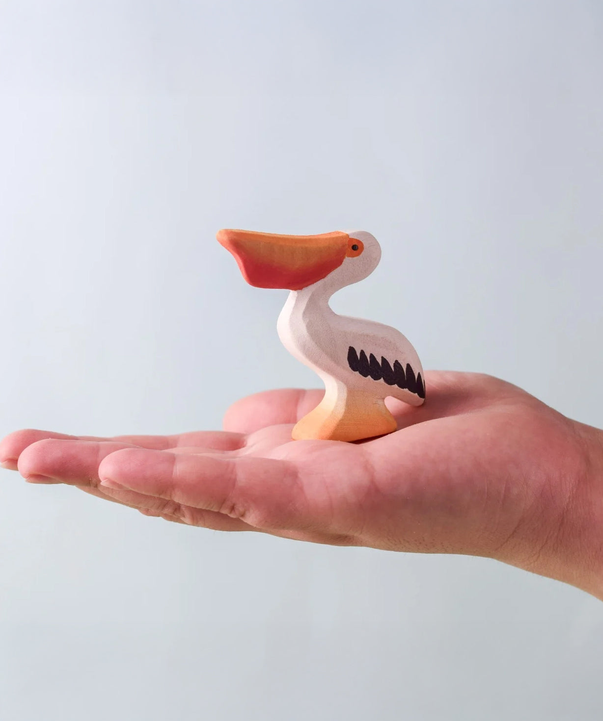 Bumbu Toys' Eating Pelican, being held in an adult's hand.