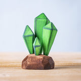 Bumbu Toys Green Crystals handmade wooden figure placed on a wooden surface. These crystals are part of a large range of wooden toys available at Babipur.