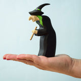 A Bumbu Toys Wooden Brewing With Figure balancing on the palm of an adult's hand. 