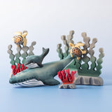 A Bumbu Toys Blue Whale handmade wooden toy figure placed at the centre of a underwater themed small world play scene. 