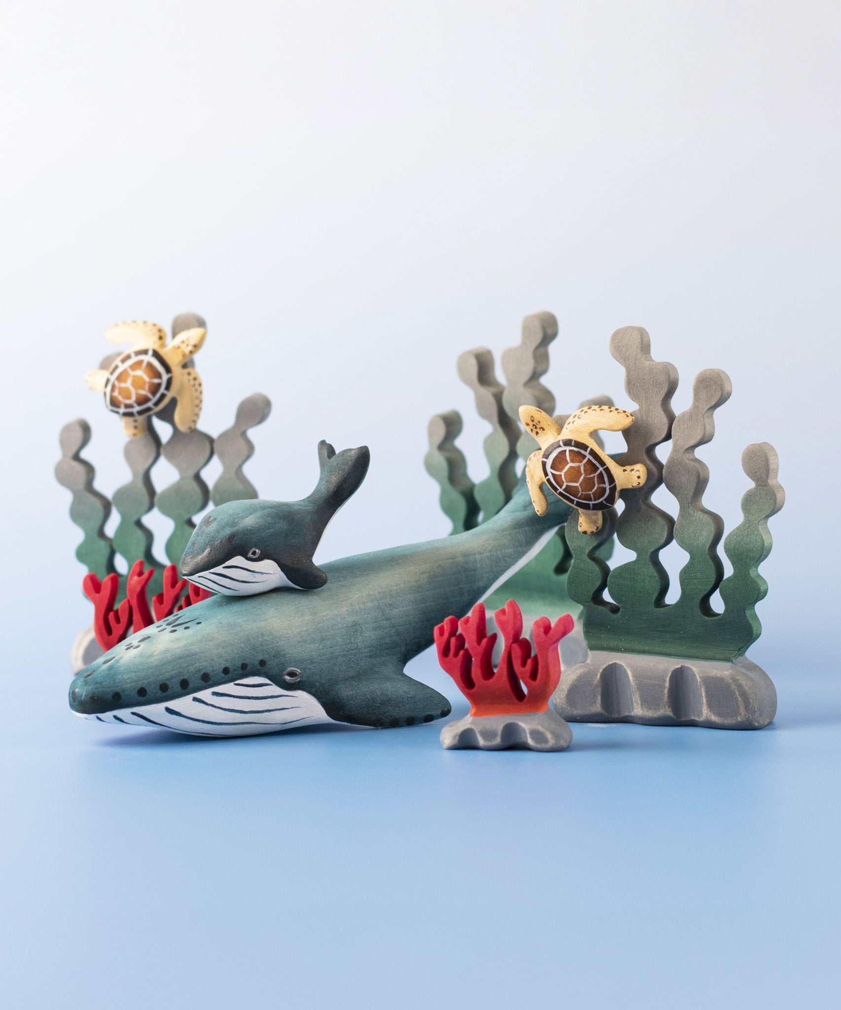 A Bumbu Toys Blue Whale handmade wooden toy figure placed at the centre of a underwater themed small world play scene. 