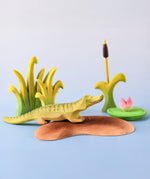Bumbu Toys' Little Island in a scene with Bumbu's baby Crocodile, Reed, Water Lily and Cattails.