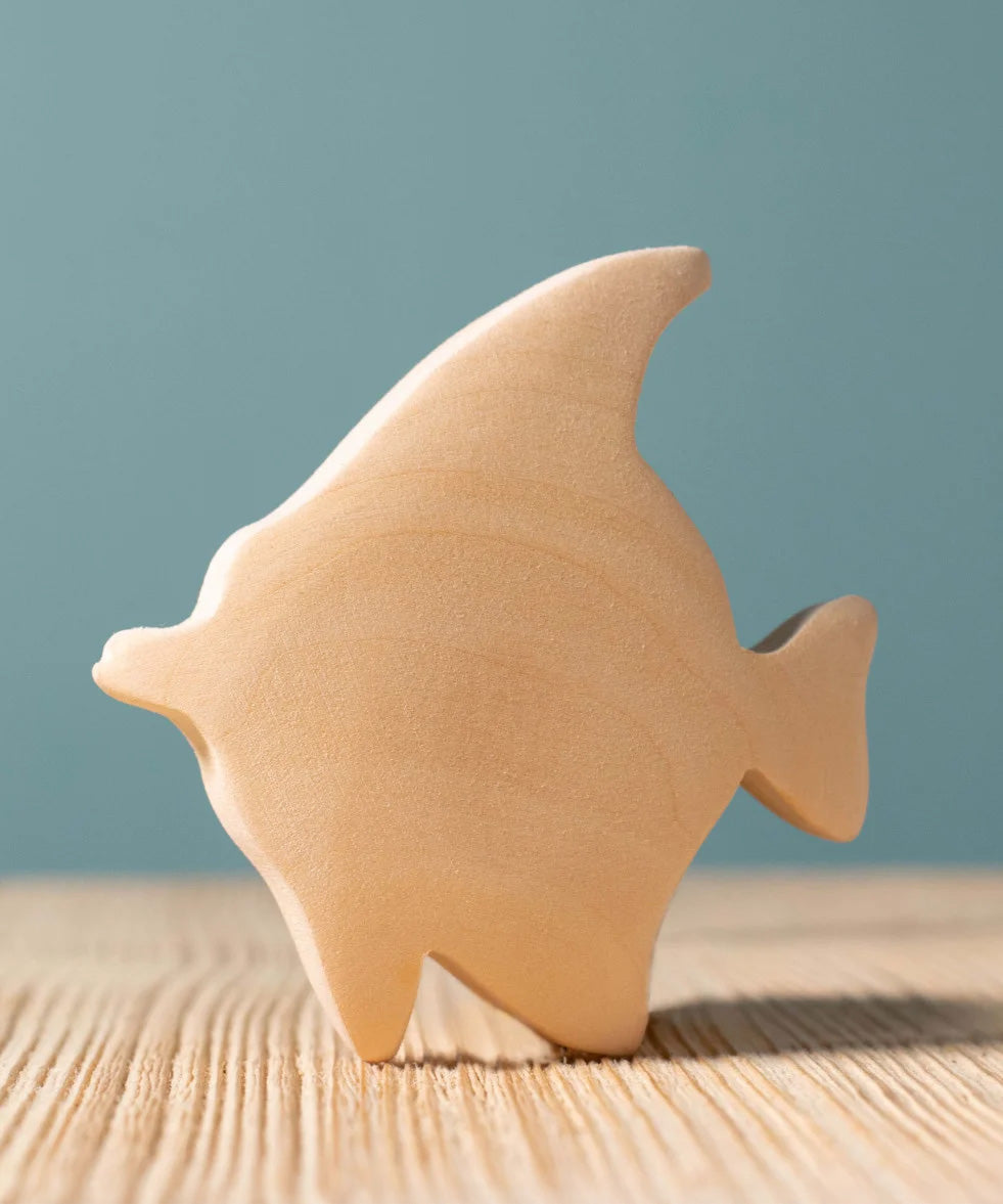 A Bumbu Moorish Idol Fish wooden figure placed on a wooden surface. This figure is part of a larger range of wooden paint your own toys. 
