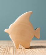 A Bumbu Moorish Idol Fish wooden figure placed on a wooden surface. This figure is part of a larger range of wooden paint your own toys. 