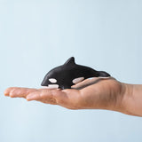 A Bumbu Toys Baby Orca placed on the palm of an adult's hand to show scale.