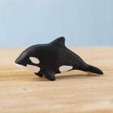 A Bumbu Toys Baby Orca placed on a wooden toy surface. 