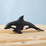 A Bumbu Toys Orca handmade wooden toy figure placed on a wooden surface. The Orca whale is part of a large range of handmade wooden toys here at Babipur.