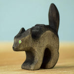 Bumbu Toys Scared Black Cat figure. The cat's tail is stood up and the cat has green eyes. The cat is placed on a wooden surface.