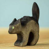 Bumbu Toys Scared Black Cat figure. The cat's tail is stood up and the cat has green eyes. The cat is placed on a wooden surface.