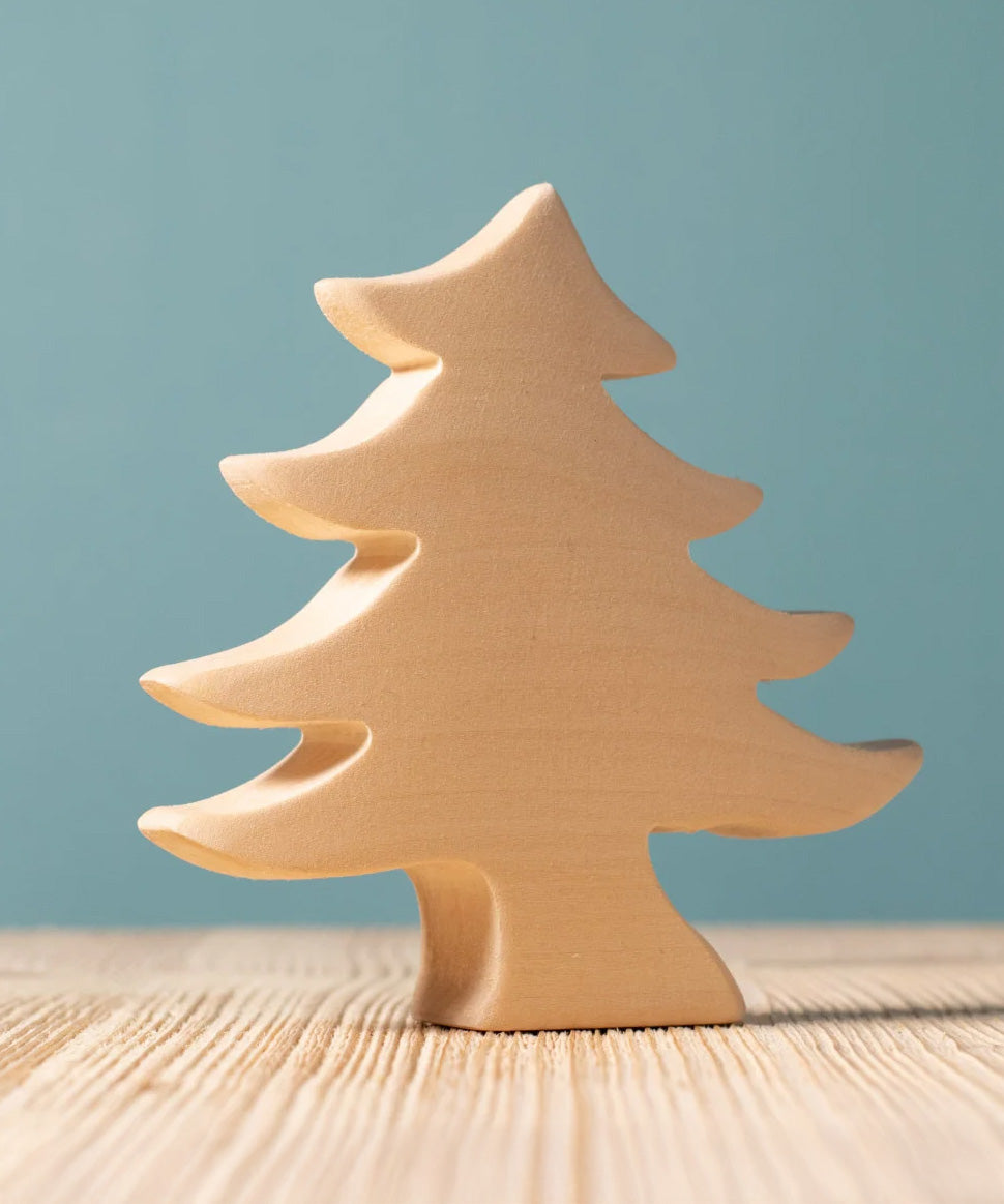 A Bumbu Toys Small Spruce Paint Your Own wooden figure placed on a wooden surface. The wooden DIY figure is part of a larger collection of paint your figure collection at Babipur.