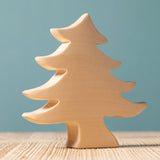A Bumbu Toys Small Spruce Paint Your Own wooden figure placed on a wooden surface. The wooden DIY figure is part of a larger collection of paint your figure collection at Babipur.