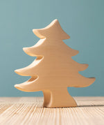 A Bumbu Toys Small Spruce Paint Your Own wooden figure placed on a wooden surface. The wooden DIY figure is part of a larger collection of paint your figure collection at Babipur.