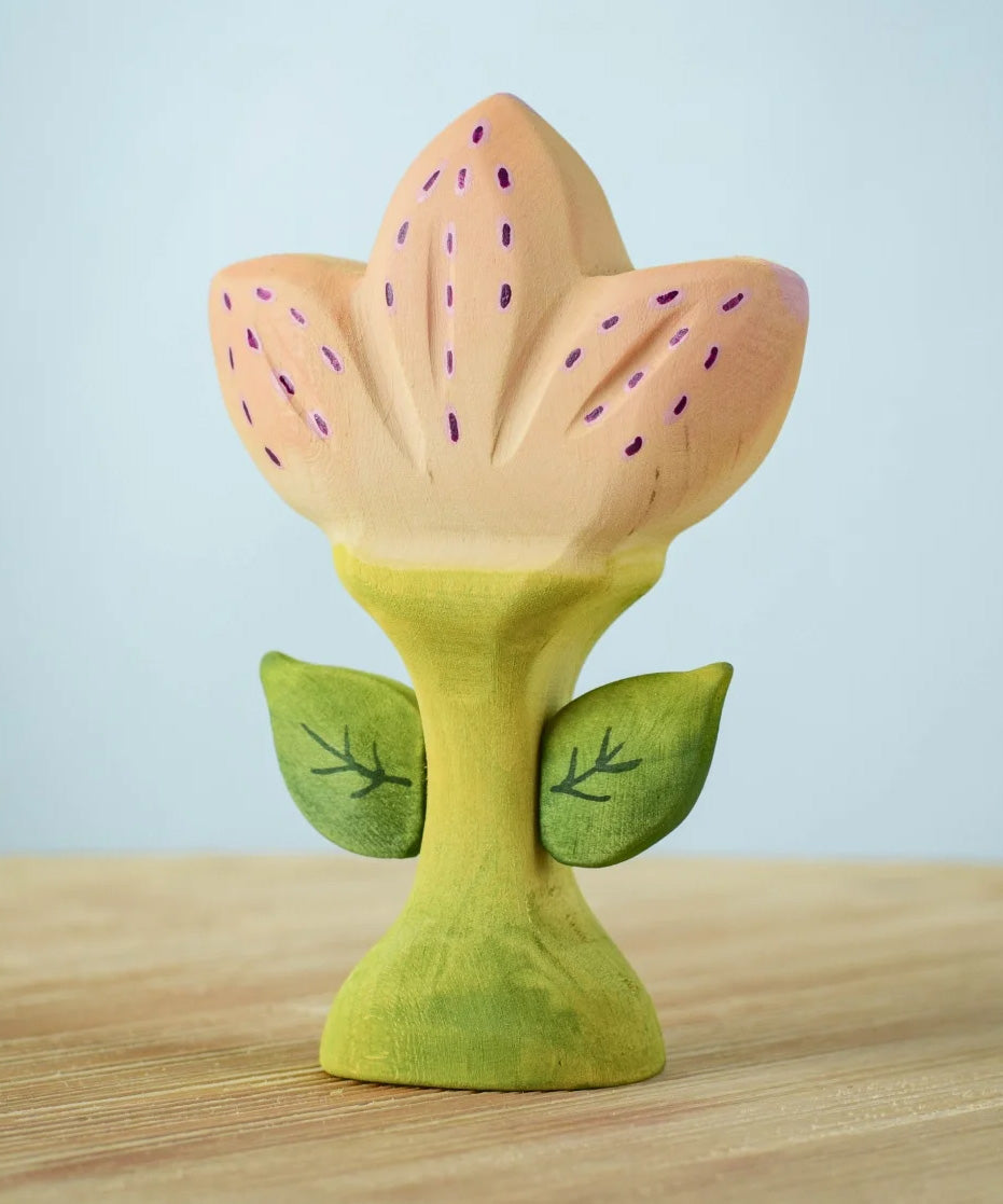 The Bumbu Toys Zia Spring Flower has a pinky peach coloured flower with purple detailing and a green coloured stem. 