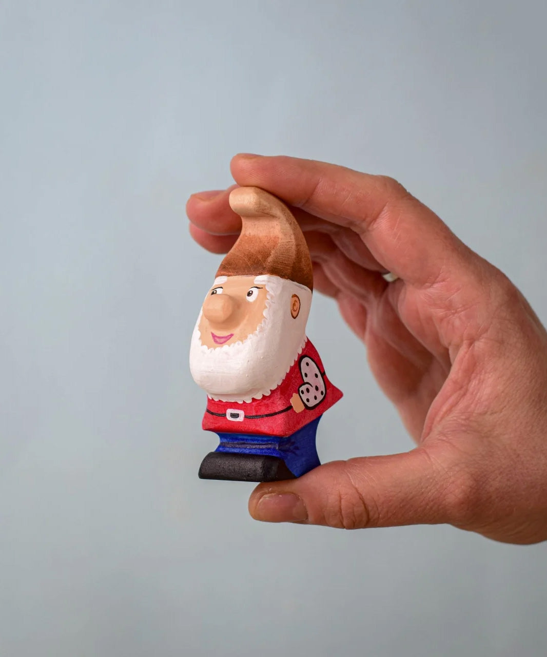 The Bumbu Toys Whittle Dwarf shown in an adult's hand. 