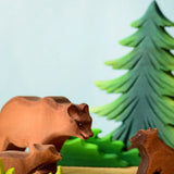 Play scene showing Bumbu toys handcrafted wooden brown standing bears and a fir tree figure in the background