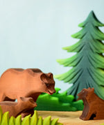 Play scene showing Bumbu toys handcrafted wooden brown standing bears and a fir tree figure in the background