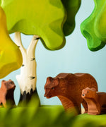 Play scene showing Bumbu toys handcrafted wooden brown standing bears and trees in the background