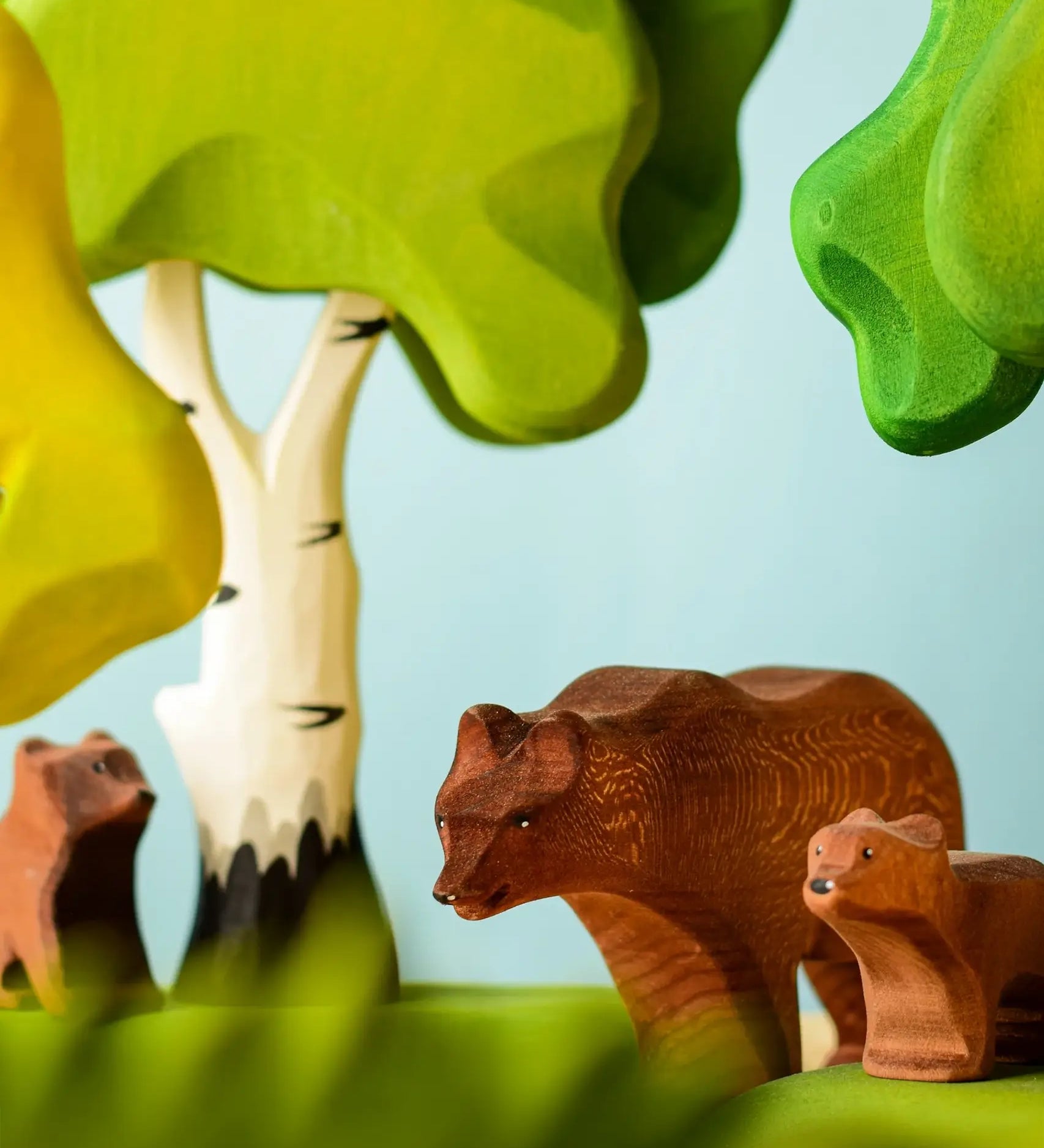 Play scene showing Bumbu toys handcrafted wooden brown standing bears and trees in the background