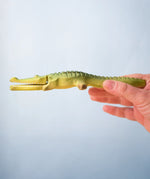Bumbu Toys' Wooden Crocodile, being held by an adult's hand.