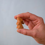 The Bumbu Toys wooden baby rabbit, in a curious upright position, held in a hand for size reference