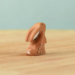 A back view of The Bumbu Toys wooden baby rabbit, in a curious upright position.