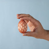 A Bumbu wooden toy egg shown in an adult's hand for scale. The wooden egg is part of our Bumbu wooden toy collection here at Babipur. 