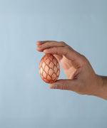 A Bumbu wooden toy egg shown in an adult's hand for scale. The wooden egg is part of our Bumbu wooden toy collection here at Babipur. 