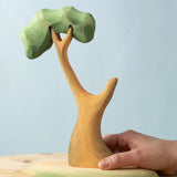 An adult's hand on the Bumbu Toys Eucalyptus Tree.