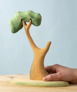 An adult's hand on the Bumbu Toys Eucalyptus Tree.