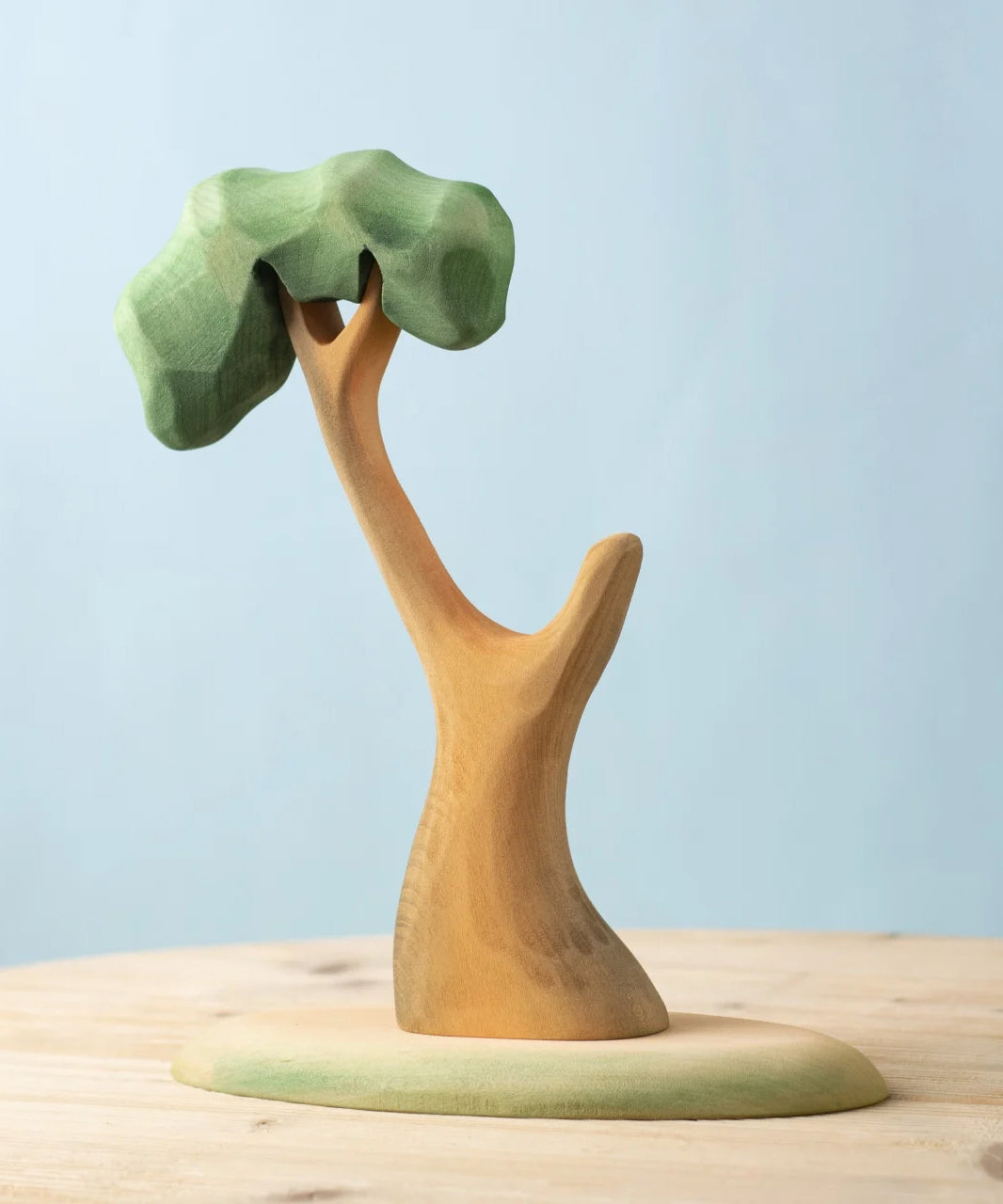 A Bumbu Toys Eucalyptus Tree placed on a wooden surface. These handmade wooden figures make wonderful scenery for small world play that pair well with our collection of wooden toy figures here at Babipur. 