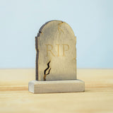 The RIP decorated headstone from the Bumbu Toys Gravestones Set. The headstone is placed on a wooden surface.
