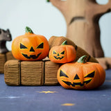 The Bumbu Toys Halloween Pumpkins Set placed in a small world play scvene with other wooden Bumbu toys including hay bales and a spooky tree in the background. 